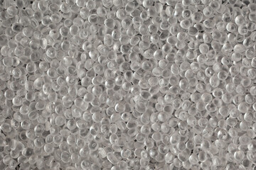 Texture of virgin polystyrene granules, close-up. Granulated plastic polymer. PS granules, transparent beads. Virgin GPPS pellets