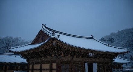 Traditional Korean temple covered with snow in winter evening, serene architecture in blue twilight with calm atmosphere and historical heritage