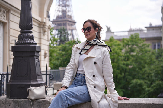 Chic woman in trench coat posing near Eiffel Tower in Paris - Powered by Adobe