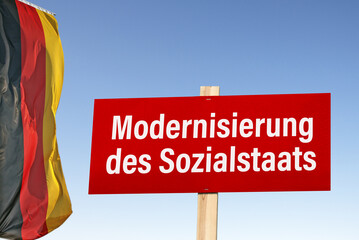 Schild mit der Devise; Modernisierung des Sozialstaats und deutscher Flagge