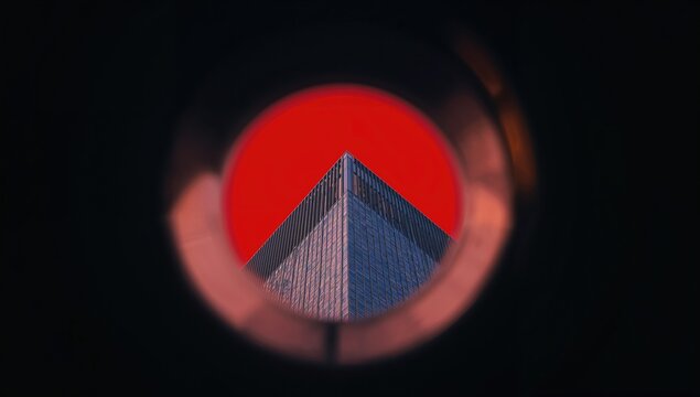 Architectural structure framed by a circular red backdrop, artistic close-up in an urban setting