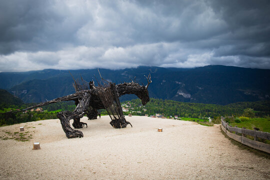 Lavarone, Trentino, Italy - september 2025: The terrific Drago Vaia, world's largest wooden dragon sculpture by artist Martalar, on a cloudy day with dark stormy sky. Side view, entire body.
