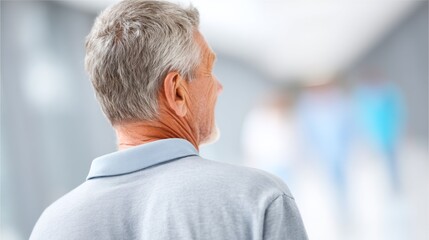 A thoughtful elderly man walks slowly down a long, serene hallway. The soft light highlights his gray hair as he contemplates the moments of his past, creating a sense of nostalgia