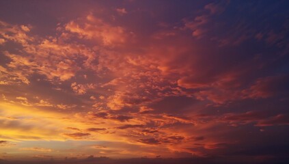 Fototapeta premium Evening Sky at Dusk Featuring Vibrant Orange, Yellow, Pink, and Red Hues with Intense Storm Clouds and a Golden Horizon in a Summer Landscape
