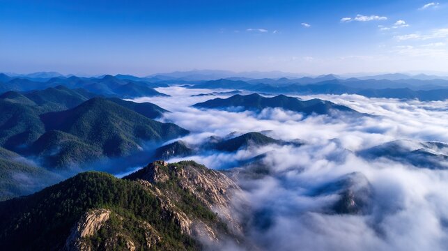 The mountains are shrouded in a light mist, with dense clouds floating over the peaks, presenting a sense of vastness and tranquility, creating a peaceful and expansive natural landscape.