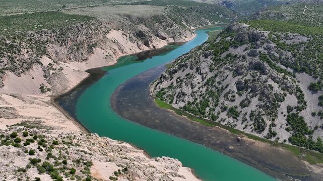 Zrmanja canyon river from Obrovac to river mouth aerial. Aerial shots of winding Zrmanja river cutting through deep canyon, lush spring colors and remote paths