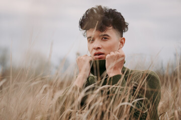 An authentic candid portrait of a young man in tall grass, capturing genuine expression, textured...