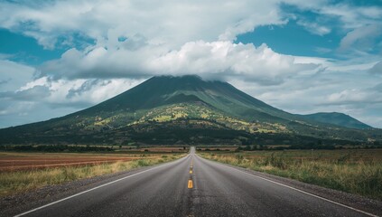 Fototapeta premium Deserted roadway flanked by lush hills under a cloudy sky
