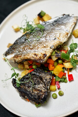 Crispy-skinned sea bass rests atop a bed of colorful diced vegetables and pea greens, delivering a vibrant, healthy seafood dish ideal for gourmet menus and editorial food photography.