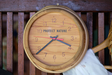 A wooden wall clock displays the time, but it also says PROTECT NATURE in the upper half, serving...