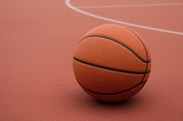 Obraz premium Close-up of a basketball resting on a red sports surface