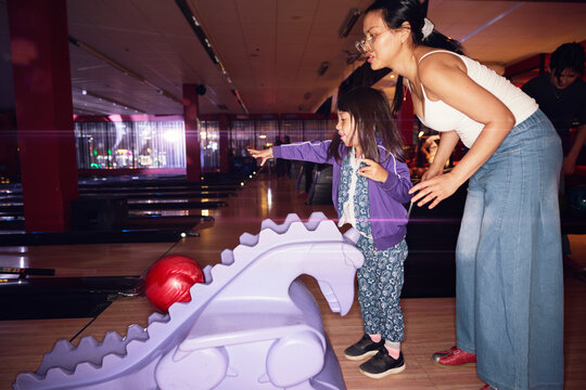 Mother and daughter spending leisure time at bowling alley