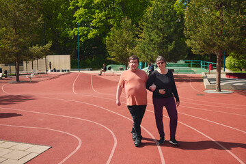 Man with autism walking arm in arm with mother on track in park
