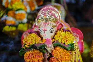 Beautifully decorated Lord Ganesha idol adorned with vibrant marigold flowers during festival puja,...