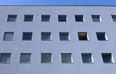 Blue gray plaster facade with square windows. Bottom view, background and texture.