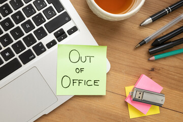 Green Sticky Note with “Out of Office” Message on Desk