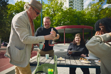 Senior man packing up things after spending leisure time with family friends in park