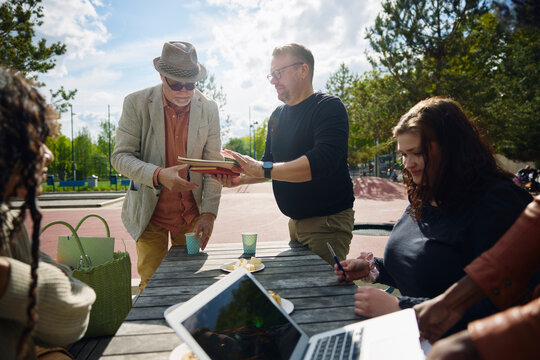 Man helping senor male friend in packing things at park on sunny day