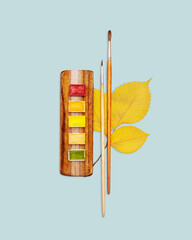 Autumn Watercolor Palette With Brushes And Yellow Leaves On Pastel Blue Background For Seasonal Creativity, Art Education, DIY Projects, And Minimalist Visual Storytelling