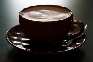 A backlit shot of a ceramic cup of cappuccino 