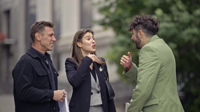 Happy business colleagues discuss, agree, and celebrate their shared project success and teamwork outdoors.