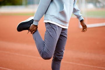 Athlete warming up, stretching leg on track
