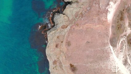 Aerial top down view of rocky shore and turquoise ocean. Media