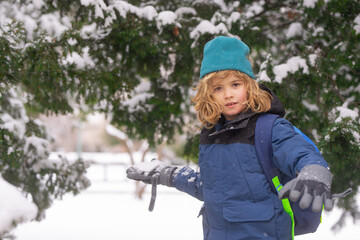 Kid play with snow in winter park. Winter kids with first snow. Child winter holiday. Smiling boy...
