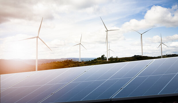 Wind turbines and Solar panels park at sunset.Windmill turbines generating green energy electric.Green energy reduce carbon emissions and makes earth cleaner and more ecological.