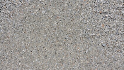 Detailed close-up of a rough concrete surface with embedded small stones and pebbles in a smooth gray base