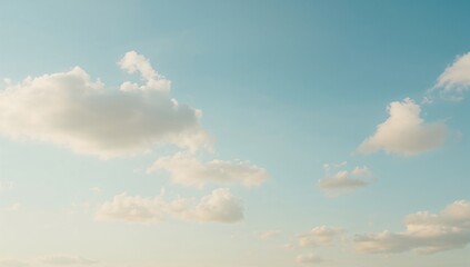 Obraz premium Soft sunlight illuminating white clouds against a gentle blue sky, highlighting a peaceful natural scene.