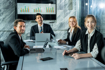 multiracial business team smiling during casual moment in office meeting room group of asian male and caucasian coworkers seated around table showing positive team atmosphere and workplace unity