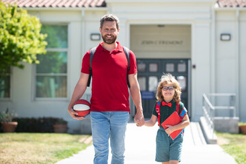 Father and son walk near school park outdoor.