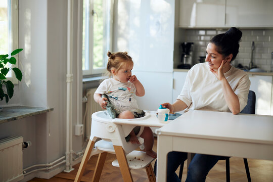 Mother and daughter spending leisure time sitting at dining table