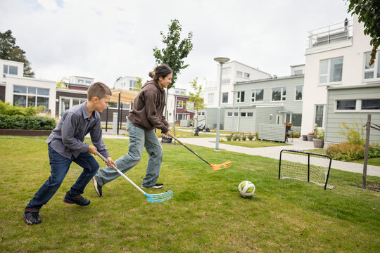 Happy woman and her son playing floorball in garden