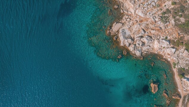 Bird's eye drone shot showcasing pristine waters at a stunning coastal cove in the eastern region of Sardinia, surrounded by natural beauty.