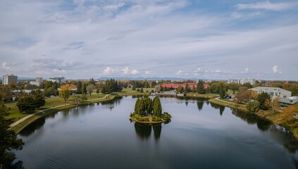 Obraz premium Overcast weather over a park with lake and island captured by drone