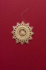 Snowflakes are made of straw on a red background. Christmas decor. Straw star. Top view. Straw weaving. Lutsk, Ukraine
