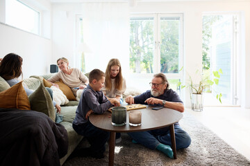 Grandparents spending leisure time with grandchildren playing games at home