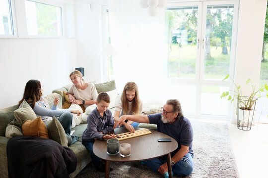 Grandparents spending leisure time with children sitting in living room