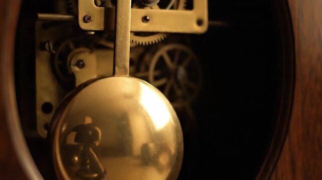 Close up of a pendulum clock mechanism with gears and a golden weight