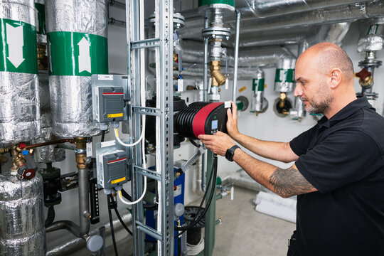 Maintenance engineer programming machine inside boiler room at factory