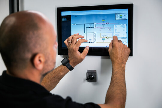 Man programming controls through digital tablet at factory