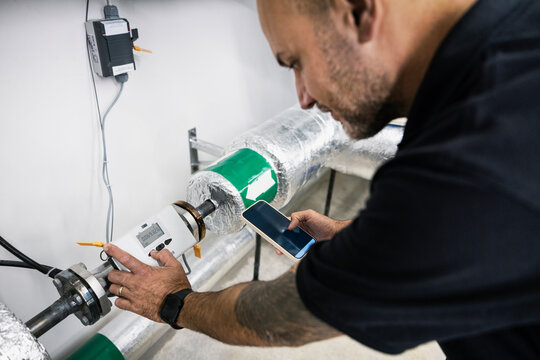 Over the shoulder view of engineer programming machine through smart phone