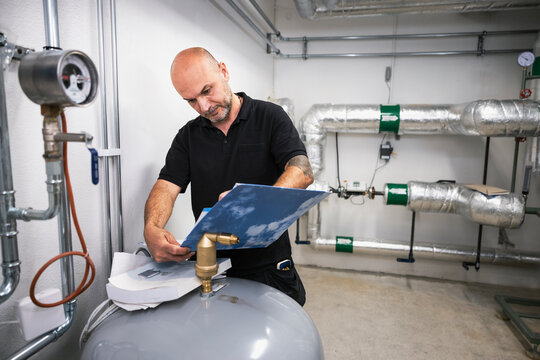 Technician examining documents while working at factory