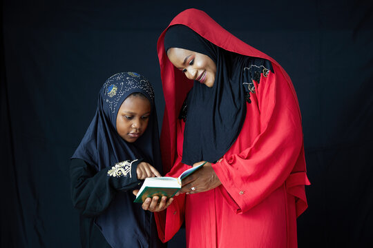 Muslim family, mother teaching her daughter, woman reading Quran black background, This scene evokes warmth and connection between a mother and child