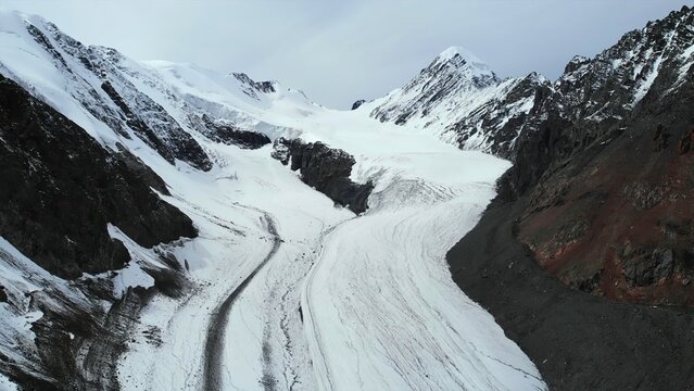 Majestic mountain glacier winds through snowy peaks. Media