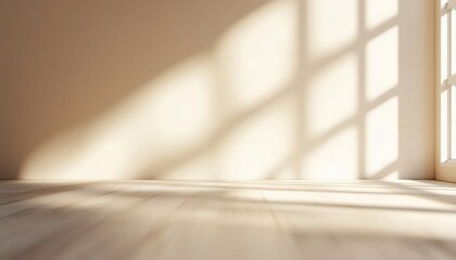 The image shows an empty room with soft sunlight casting shadows on a light beige wall and a light wood floor, creating a serene atmosphere.