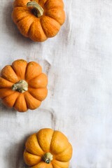 Three mini orange pumpkins on rustic linen fabric – autumn flatlay still life