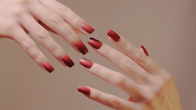 Close-up of red manicured hands, rubbing against each other and separating. Fashion nail shape and glossy of gel polish, skincare. Symbolism of separation, relationships. Beauty, nails with manicure